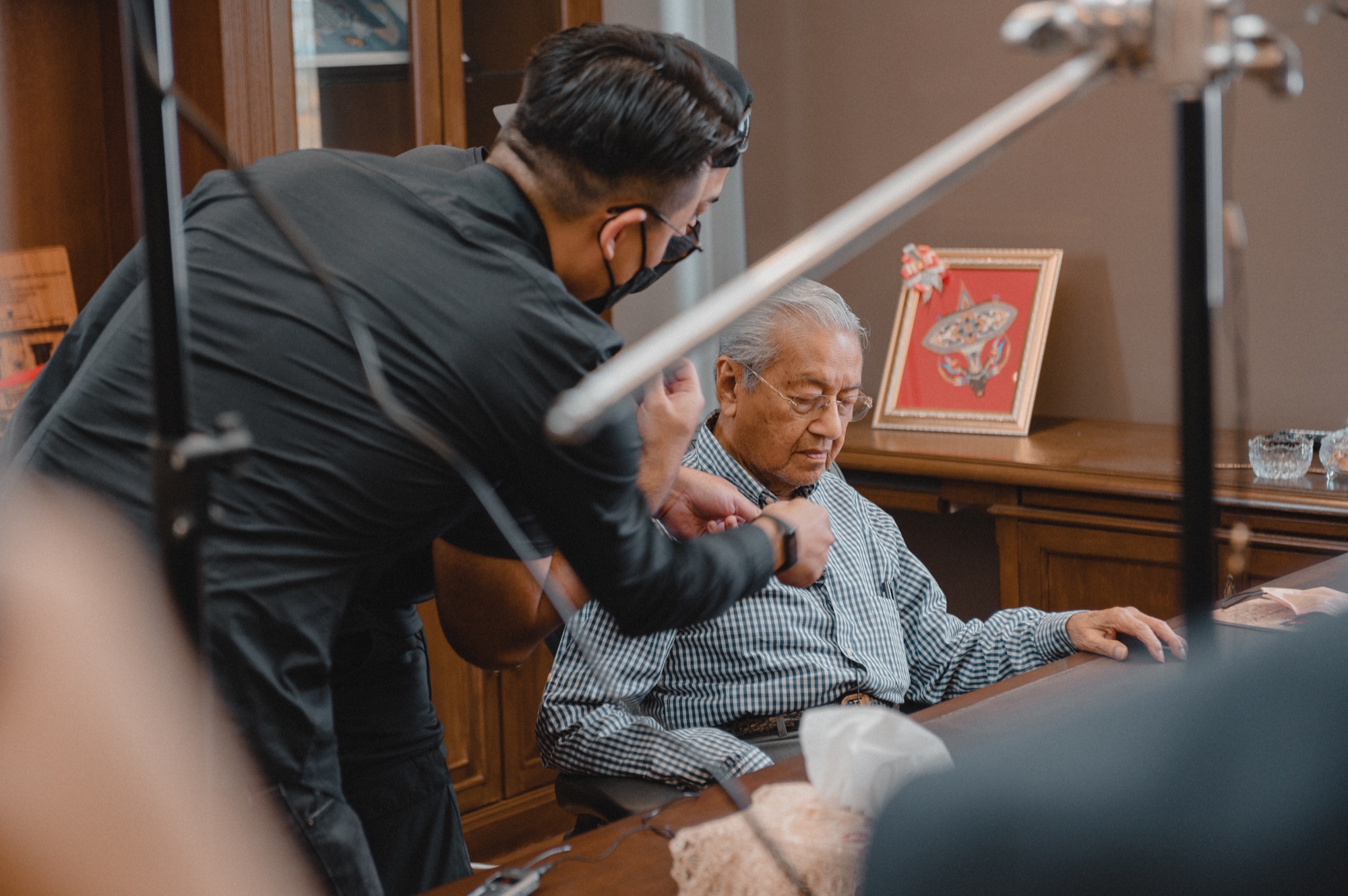 A team member preparing Tun Mahathir’s microphone before filming