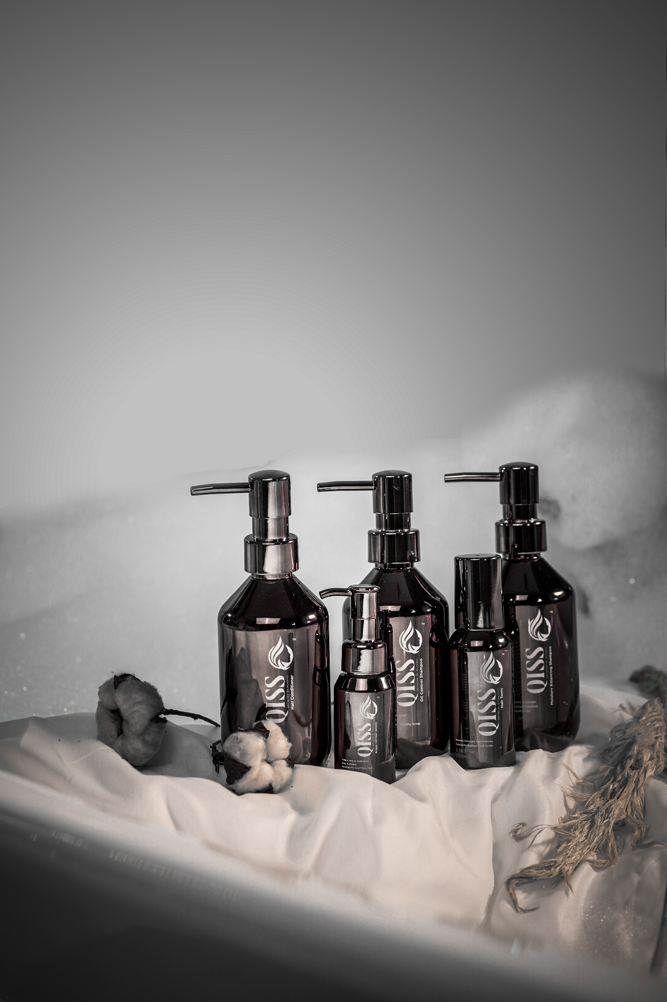 QISS haircare product collection on a stone display