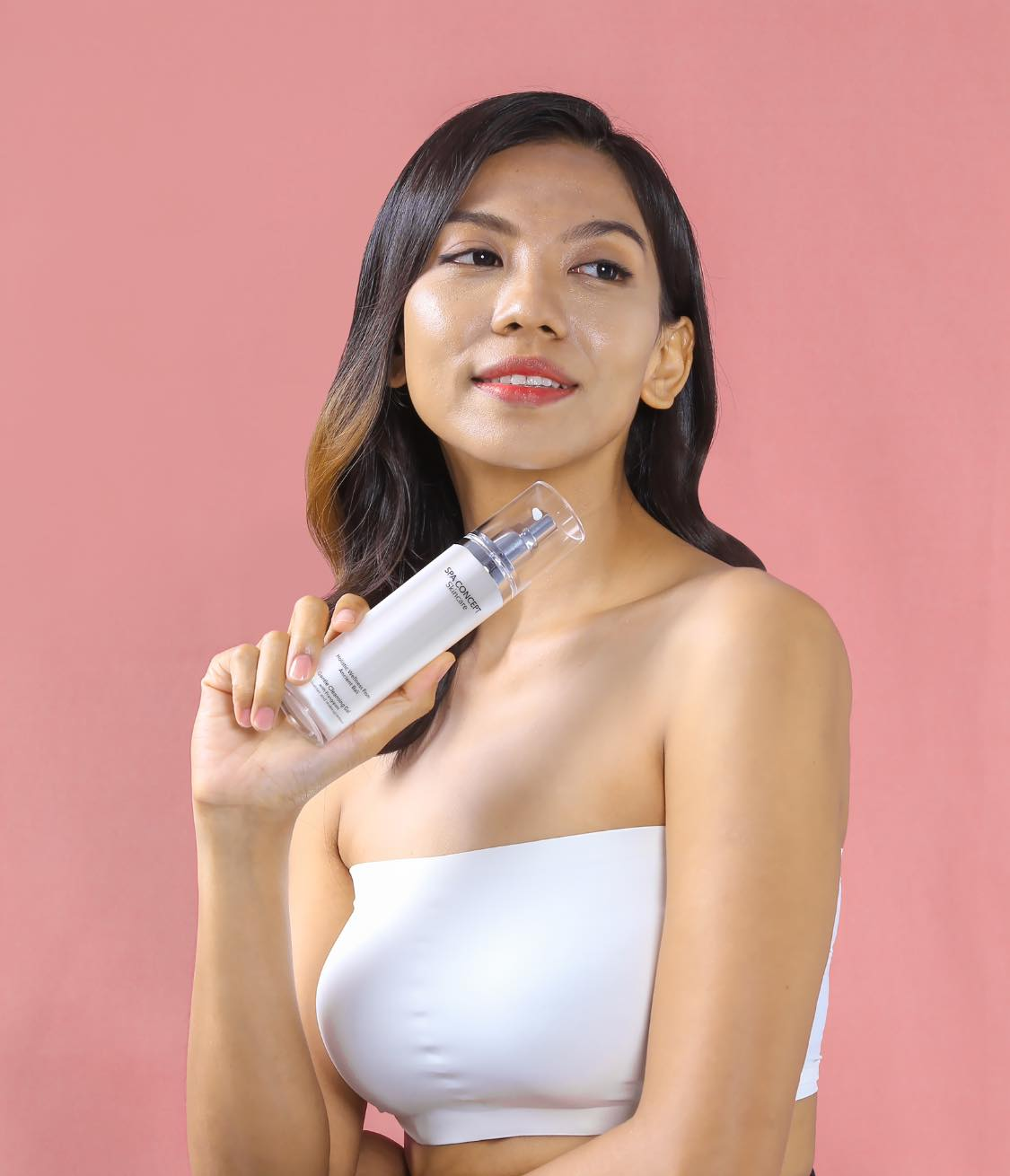 SpaConcept campaign model holding a skincare product against a pink background